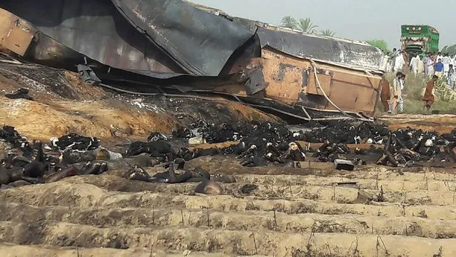 Local residents (R) look at burnt bodies after an oil tanker caught fire following an accident on a highway near the town of Ahmedpur East, some 670 kilometres (416 miles) from Islamabad on June 25, 2017. At least 123 people were killed and scores injured in a fire that broke out after the oil tanker overturned in central Pakistan early on June 25 and crowds rushed to collect fuel, an official said. (Photo by AFP Photo/Stringes)