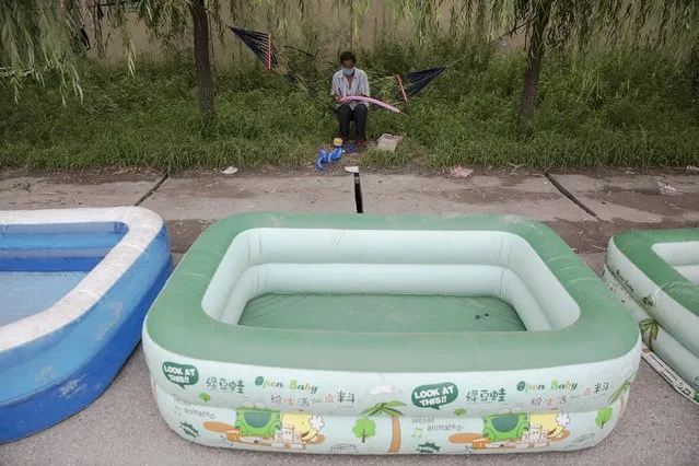 A man selling inflatable pools protects himself with a mask on a heavy polluted day inTangshan in China's Hebei Province August 3, 2015. (Photo by Damir Sagolj/Reuters)