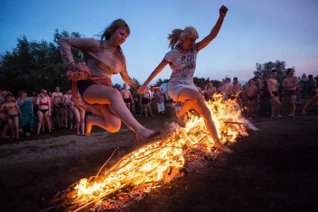 Women jump over a bonfire during festivities marking Ivan Kupala Day in Omsk, Russia on July 6, 2017. (Photo by Dmitry Feoktistov/TASS)