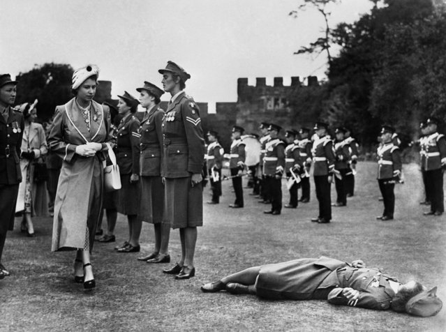 Britain's Princess Elizabeth clasps her hands in sympathy as Sergeant Jean Bayliss faints at her feet during an inspection of the guard of honour of the Women's Royal Army Corps at Shrewsbury Castle, Shropshire, on July 6, 1949. (Photo by AP Photo)