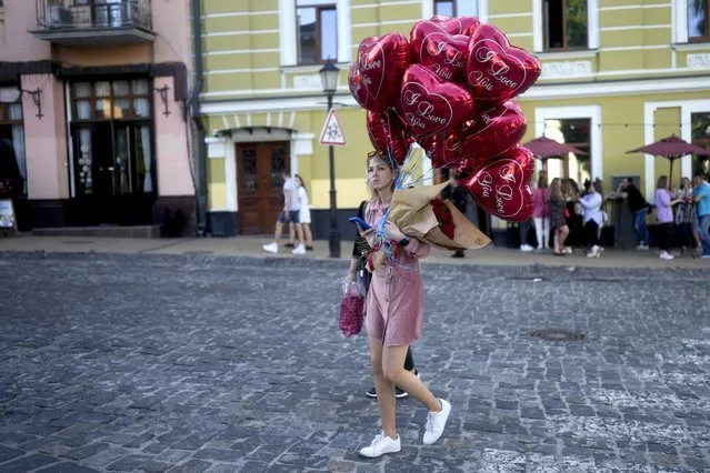 A woman crosses a street with balloons in Kyiv, Ukraine, Wednesday, June 1, 2022. (Photo by Natacha Pisarenko/AP Photo)