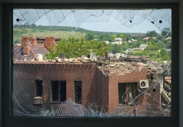 A heavily damaged house following Russian night shelling is seen through a broken window, in the town of Bakhmut, Donetsk region, Ukraine, Monday, June 13, 2022. (Photo by Efrem Lukatsky/AP Photo)
