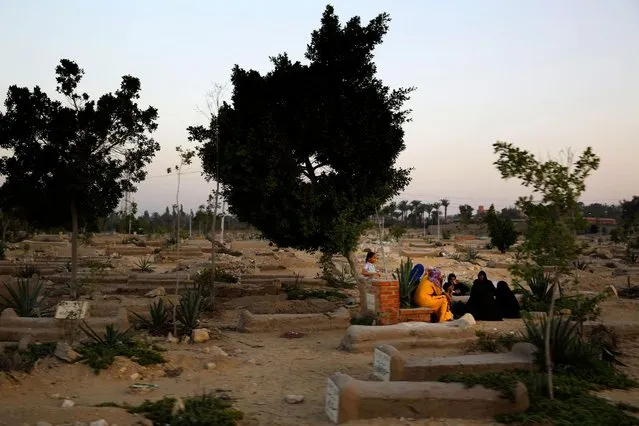 Egyptian women sit next to a grave in a cemetery as the sun sets in Cairo, Egypt, Saturday, August 1, 2015. (Photo by Hassan Ammar/AP Photo)
