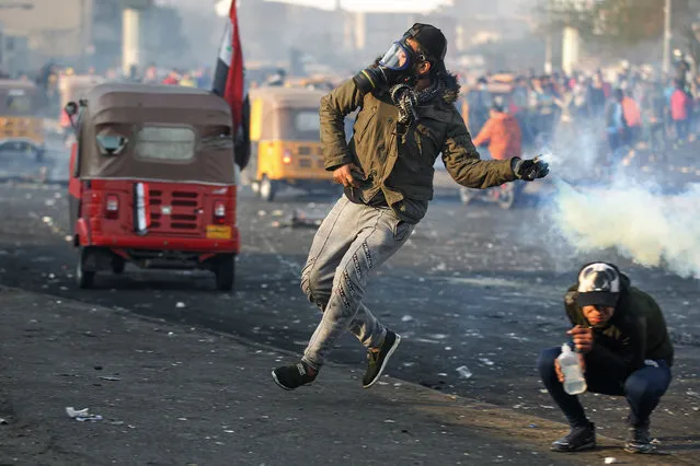 An anti-government protester throws back a tear gas canister at security forces during clashes at Tayaran Square, east of Tahrir Square in the centre of the Iraqi capital Baghdad on January 20, 2020. (Photo by Ahmad al-Rubaye/AFP Photo)