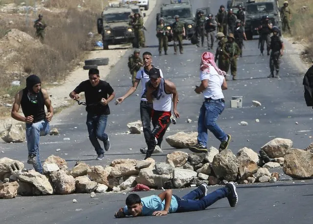 Palestinian protesters run for cover as Israeli soldiers fire rubber bullets during clashes following a demonstration against Israeli military action in Gaza, at the Beit Fourik checkpoint near the West Bank city of Nablus August 15, 2014. (Photo by Abed Omar Qusini/Reuters)