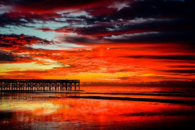 Dawn breaks behind scattered clouds causing dramatic colors over the Atlantic Ocean before sunrise on Front Beach, November 19, 2024 in Isle of Palms, South Carolina. (Photo by Richard Ellis/Alamy Live News)