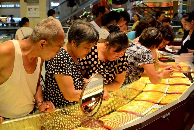 Customers look at gold necklaces at a jewelry store in Xuchang, Henan province, August 12, 2015. Gold rose for a fifth session in a row on Wednesday, hitting a fresh three-week high as the dollar and European equities slid on concerns over China's devaluation of its currency. (Photo by Reuters/Stringer)