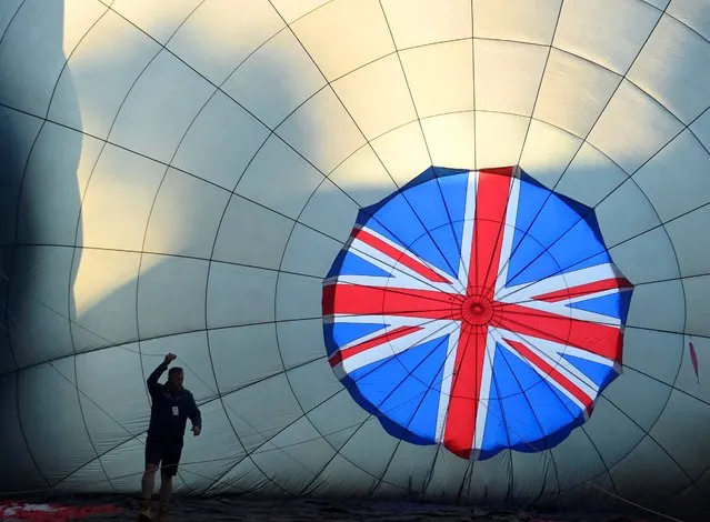 A crew member prepares a partially inflated balloon at the annual Bristol International Balloon Fiesta, near Bristol, Britain on August 12, 2022. (Photo by Toby Melville/Reuters)