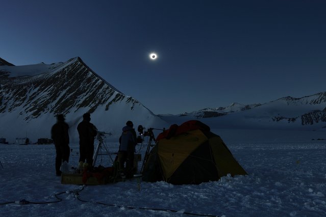 In this photo provided by Imagen de Chile, people view a total solar eclipse from Polar Union Glacier Camp in Antarctica, Saturday, December 4, 2021. (Photo by Felipe Trueba/Imagen Chile via AP Photo)