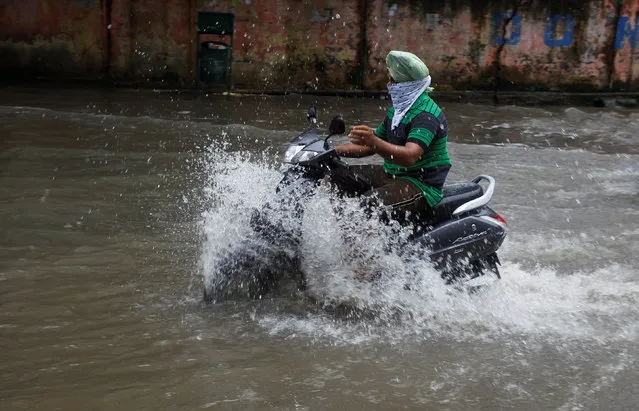 A man rides a scooter through a flooded street during heavy rains in Jammu, India, August 7, 2016. (Photo by Mukesh Gupta/Reuters)