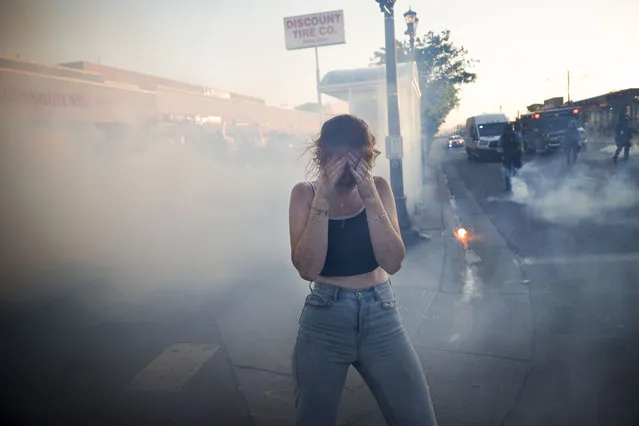 A protestor reacts as she walks through a cloud of tear gas, Thursday, May 28, 2020, in St. Paul, Minn. Protests over the death of George Floyd, a black man who died in police custody Monday, broke out in Minneapolis for a third straight night. (Photo by John Minchillo/AP Photo)