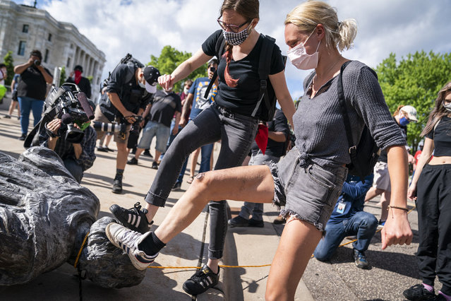 People take turns stomping the Christopher Columbus statue after it was toppled in front of the Minnesota State Capitol in St. Paul, Minn., on Wednesday, June 10, 2020. (Photo by Leila Navidi/Star Tribune via AP Photo)