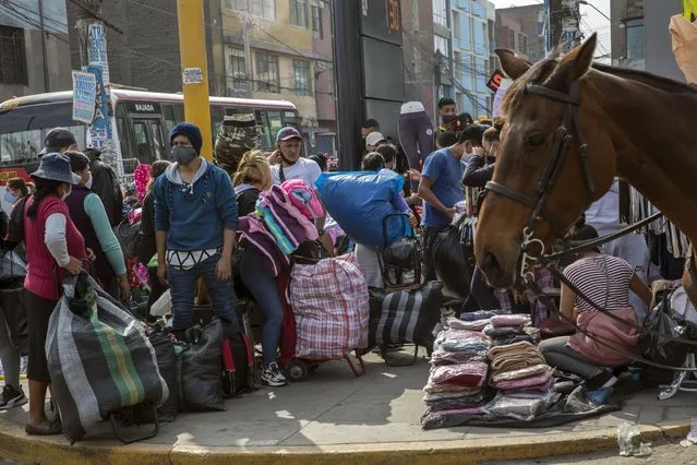 Street vendors who came out to sell their products, ignoring lockdown measures to curb the spread of the new coronavirus, wait for clients as mounted policemen patrol in La Victoria district of Lima, Peru, Friday, June 19, 2020. (Photo by Rodrigo Abd/AP Photo)