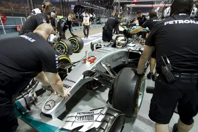 Mercedes Formula One team members push driver Lewis Hamilton of Britain into their garage at the Marina Bay street circuit during the first practice session of the Singapore F1 Grand Prix September 18, 2015. (Photo by Edgar Su/Reuters)