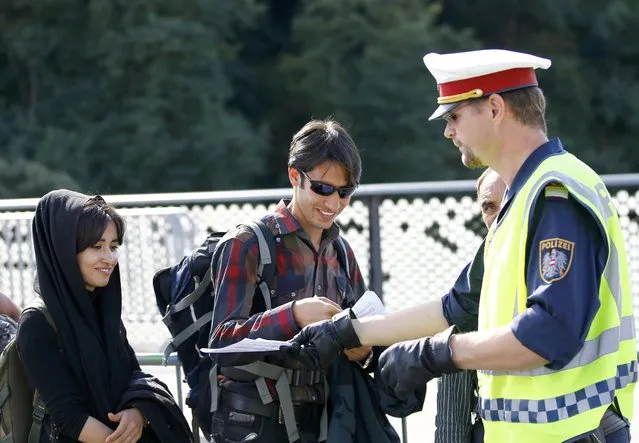 A policeman gives written instructions to migrants as they cross the border from Slovenia to Bad Radkersburg, Austria September 21, 2015. (Photo by Leonhard Foeger/Reuters)