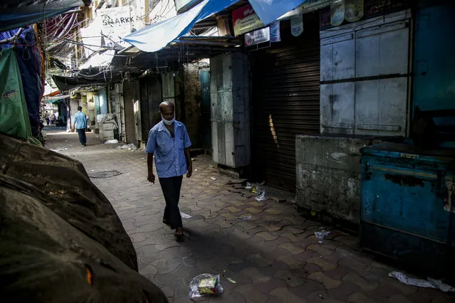 A man with a face mask hanging on his chin walks at a closed market complex in Kolkata, India, Friday, July 17, 2020. (Photo by Bikas Das/AP Photo)