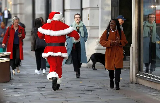Santa runs past commuters as he attends a Christmas photo-call at Hamleys toy store, in London, Britain on September 29, 2022. (Photo by Peter Nicholls/Reuters)