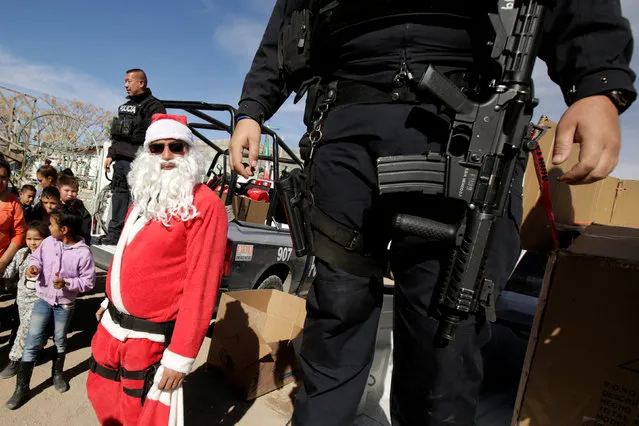 A police officer dressed as Santa Claus stands next to his colleagues after given toys to children during Three Kings day in a low income neighborhoods in Ciudad Juarez, Mexico January 6, 2018. (Photo by Jose Luis Gonzalez/Reuters)