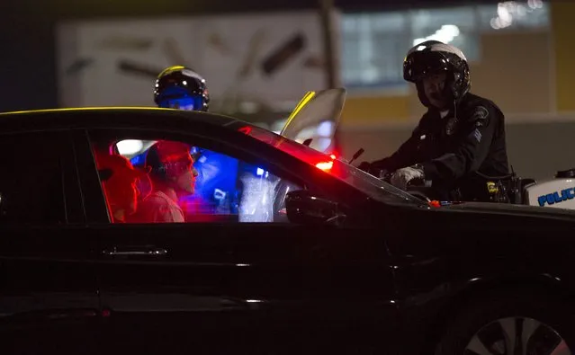 Police check two people waiting in a vehicle ahead of a possible "flash-mob" style gathering of car enthusiasts in Burbank, California October 6, 2015. (Photo by Mario Anzuoni/Reuters)