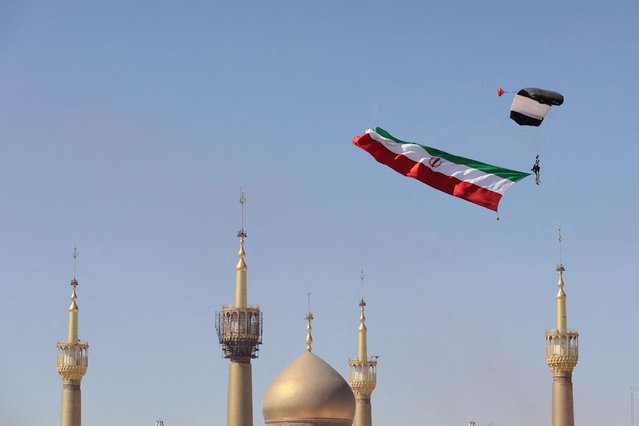 A paratrooper carries the Iranian flag over the shrine of Iran's late leader Ayatollah Ruhollah Khomeini during the National Army Day parade ceremony in Tehran, Iran on April 18, 2025. (Photo by Majid Asgaripour/WANA (West Asia News Agency)/Handout via Reuters)