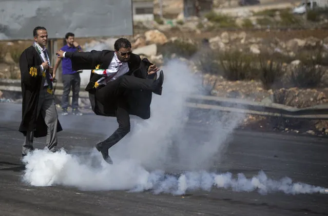 A lawyer wearing his official robes kicks a tear gas canister back toward Israeli soldiers during a demonstration by scores of Palestinian lawyers called for by the Palestinian Bar Association in solidarity with protesters at the Al-Aqsa mosque compound in Jerusalem's Old City, near Ramallah, West Bank, Monday, October 12, 2015. (Photo by Majdi Mohammed/AP Photo)