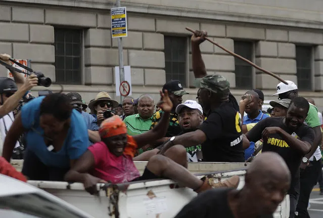 Members of the Black First Land First (BLF) sitting in the back of a pick up truck, are attacked by African National Congress (ANC) members as they protest outside the ANC headquarters in downtown Johannesburg, Monday February 5, 2018. South Africa's ruling ANC is struggling to resolve a leadership crisis amid increasing calls for scandal-tainted President Jacob Zuma to resign ahead of a key speech scheduled this week. The BLF are calling for Zuma to stay. (Photo by Themba Hadebe/AP Photo)