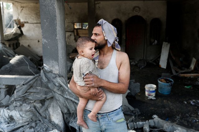 A Palestinian man holds a child at the site of an Israeli strike on a house that took place on Monday, in Zawayda in the central Gaza Strip on July 1, 2025. (Photo by Ramadan Abed/Reuters)