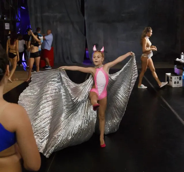 In this September 10, 2016 picture, Diana Romaniuc, 7 years-old, plays with the shiny outfit of a belly dancer before competing in the children category of the Romania Miss Pole Dance Contest, ahead of the finals of the Pole Sport&Fitness World Championship 2016 in Bucharest, Romania. (Photo by Vadim Ghirda/AP Photo)
