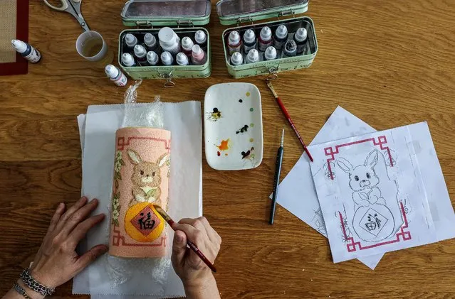 Self-taught baker Keem Ooi, 53, paints on Year of the Rabbit cakes that she sells ahead of the Lunar New Year in Kuala Lumpur, Malaysia on January 19, 2023. (Photo by Annice Lyn/Reuters)