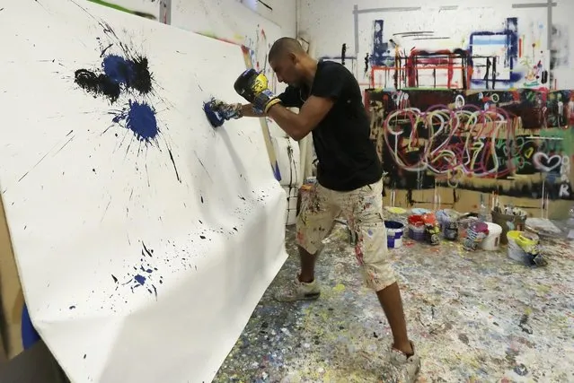 In this photo taken on Tuesday, September 6, 2016 Omar Hassan punches the canvas to paint his creations in his studio in Milan, Italy. (Photo by Antonio Calanni/AP Photo)