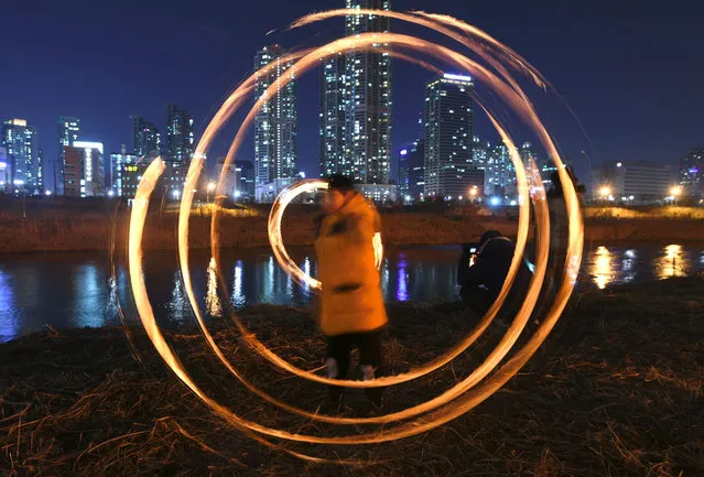 South Koreans spin cans of burning charcoal during an event marking the day before 'Jeongwol Daeboreum', a festival celebrating the first full moon of the lunar new year, at a riverside park in Seoul on March 1, 2018 Koreans traditionally mark the occasion with a game involving cans filled with burning charcoal believed to fertilize the soil and rid it of unwanted pests, ensuring a prosperous harvest. (Photo by Jung Yeon- je/AFP Photo)