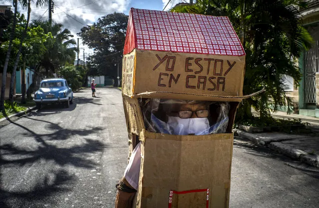 Feridia Rojas, a retired nurse, wears a cardboard box as a protective measure against the spread of the new coronavirus, in Havana, Cuba, Wednesday, July 8, 2020. The 82-year-old pensioner shuffles through the streets of Havana on shopping excursions wearing the cardboard box with a handwritten message that reads in Spanish, “I'm home”. (Photo by Ramon Espinosa/AP Photo)