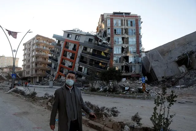 A man walks in front of semi collapsed buildings in the aftermath of a deadly earthquake in Hatay, Turkey on February 15, 2023. (Photo by Clodagh Kilcoyne/Reuters)