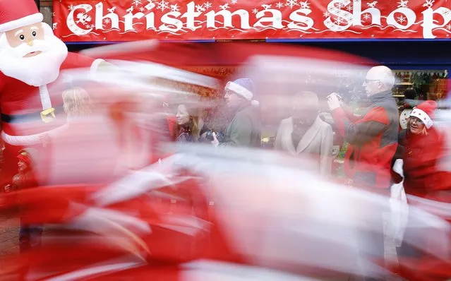 Competitors dressed as Santa Claus sprint past spectators during an annual charity Santa fun run in Loughborough, central England December 7, 2014. (Photo by Darren Staples/Reuters)