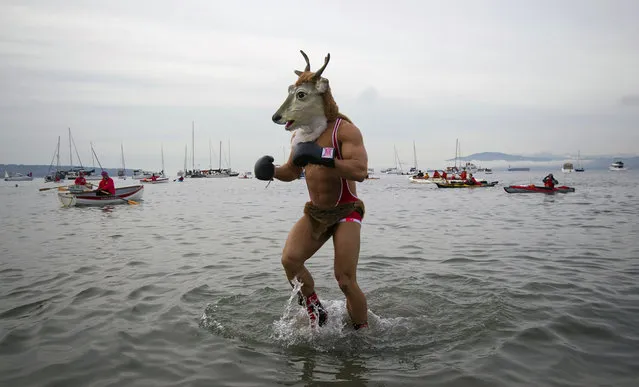 A man wearing a mask runs into English Bay during the annual New Year's Day Polar Bear Swim in Vancouver, British Columbia, on January 1, 2013. (Photo by Ben Nelms/Reuters /The Atlantic)
