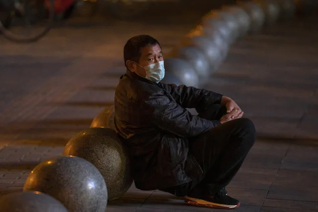 A man wearing a mask rests near barriers outside a shopping mall in Beijing on Friday, October 30, 2020. China has managed to stem the spread of the coronavirus within the country even as the pandemic continues to surge globally. (Photo by Ng Han Guan/AP Photo)