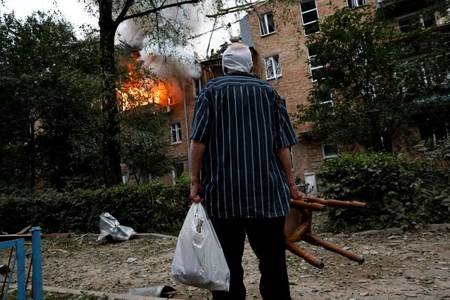 An injured resident stands outside his damaged house during Russian missile and drone strikes, amid Russia's attack on Ukraine, in Kyiv, Ukraine on July 31, 2025. (Photo by Thomas Peter/Reuters)