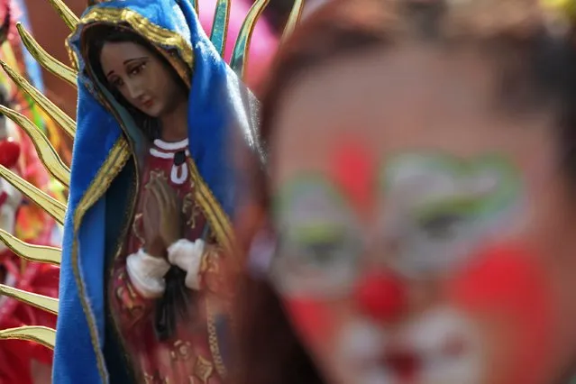 A figurine of the Virgin of Guadalupe is seen as clowns make their annual pilgrimage to the Basilica of Our Lady Guadalupe to pay homage to the Virgin of Guadalupe in Mexico City December 16, 2014. (Photo by Carlos Jasso/Reuters)