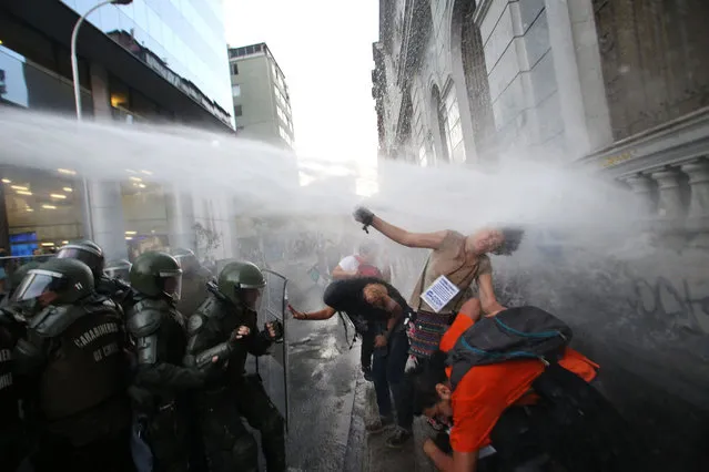 Students clash with riot police outside the Education Ministry building during a protest in Santiago, Chile on March 27, 2018, after Chile's constitutional court struck down a law that would have banned universities operating for profit, dealing a blow to free tuition reforms brought in by former leftwing president Michelle Bachelet. (Photo by Claudio Reyes/AFP Photo)