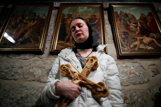 A worshipper holds a cross as she takes part in the Good Friday procession in the Church of the Holy Sepulchre in Jerusalem's Old City April 6, 2018. (Photo by Corinna Kern/Reuters)