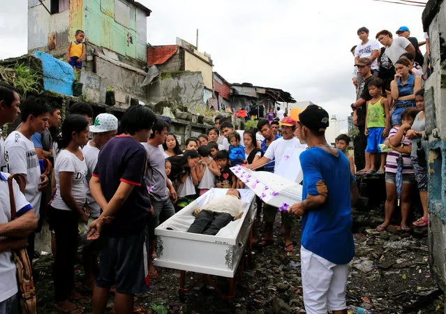 Relatives and friends gather in front of the coffin to view the body of Apolinario Eyana Jr., who was killed by unidentified men, during his burial rites inside the public cemetery in Navotas city, metro Manila, Philippines October 16, 2016. (Photo by Romeo Ranoco/Reuters)
