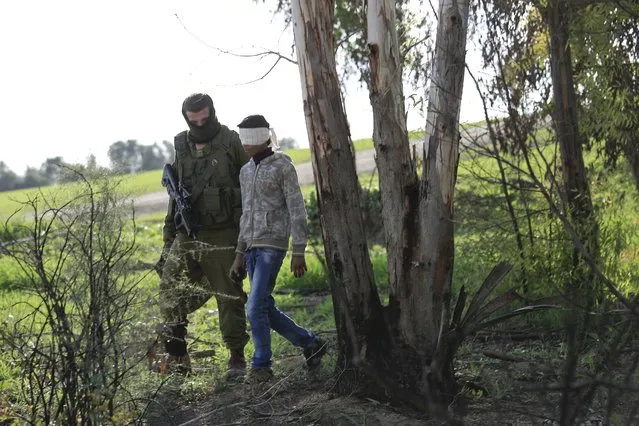 An Israeli soldier walks with a detained Palestinian teenager who military said illegally crossed into Israel near the Israel Gaza border, Wednesday, December 24, 2014. The Israeli military said it deployed tank fire and an airstrike on targets in Gaza after its troops came under attack by Palestinian snipers as they were on patrol on the Israeli side of the border. (Photo by Tsafrir Abayov/AP Photo)