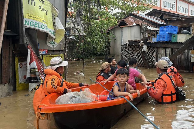 This handout photo taken and released on November 4, 2025 by the Philippine Coast Guard (PCG) shows coast guard personnel evacuating people from their flooded homes following heavy rains brought about by Typhoon Kalmaegi in Cebu province, central Philippines. Residents sought refuge on rooftops and cars floated through flooded streets on November 4 as Typhoon Kalmaegi battered the central Philippines, leaving at least two people dead. (Photo by Handout/Philippine Coast Guard (PCG)/AFP Photo)