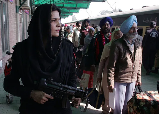 A Pakistani female police commando stands guard, as Indian Sikh pilgrims arrive at Wagah railway station near Lahore, Pakistan, Friday, November 20, 2015. Hundreds of Indian Sikh pilgrims arrived in Pakistan by a special train to participate in three-day festival to celebrate the 547st birth anniversary of their spiritual leader Baba Guru Nanak, the founder of Sikh religion, at Nankana Sahib near Lahore. (Photo by K.M. Chaudary/AP Photo)