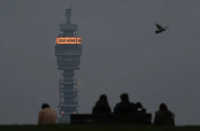 People look out from the top of Primrose Hill, with a government public health message seen displayed behind on a communications tower, amid the spread of the coronavirus disease (COVID-19) pandemic, London, Britain, January 15, 2021. (Photo by Toby Melville/Reuters)