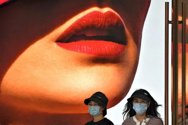 Women wearing face masks walk by a lipstick advertisement on display at a shopping mall in Beijing, Monday, May 15, 2023. (Photo by Andy Wong/AP Photo)