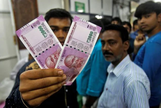 A man displays the new 2000 Indian rupee banknotes after withdrawing them from State Bank of India in Agartala, India November 11, 2016. (Photo by Jitendra Prakash/Reuters)