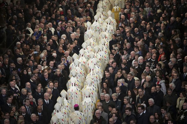 Guest watch clergy members leaving the inaugural mass at Notre Dame Cathedral, hosting its first Mass since the catastrophic fire of 2019,, Sunday, December 8, 2024 in Paris. (Photo by Alessandra Tarantino/AP Photo)