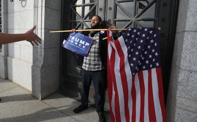 Donald Trump supporter Kern Carlos Huerta stands in front of the Utah State Capitol building doors as demonstrators protest against the election of Republican Donald Trump as President of the United States approached in Salt Lake City, Utah, U.S. November 12, 2016. (Photo by Jim Urquhart/Reuters)