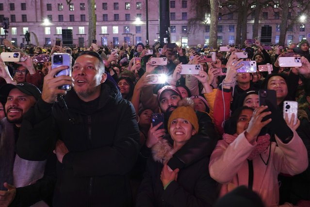 People look up, watch and take photos as fireworks light up the sky around the London Eye to celebrate the New Year in London, Wednesday, January 1, 2025. (Photo by Alberto Pezzali/AP Photo)